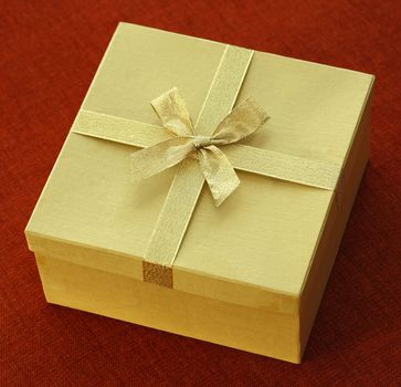 Golden gift box with bow tie on black cloth background