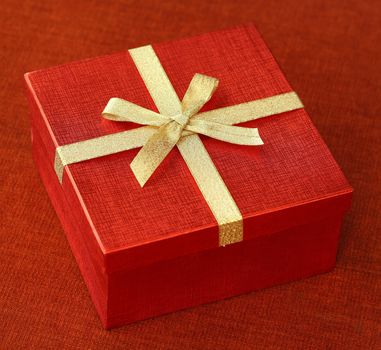 Red gift box with bow tie on red cloth background