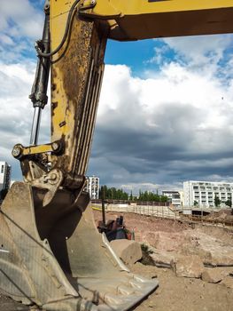Closeup of a excavator shovel, new apartments in the background