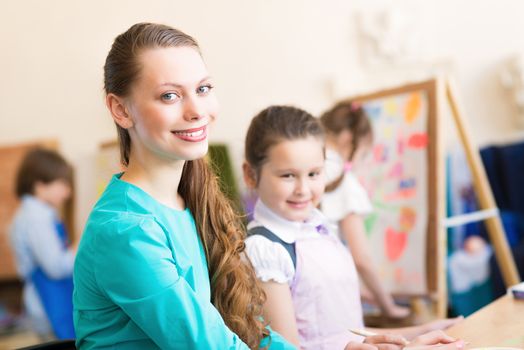 children with the teacher engaged in painting at an art school