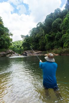 fly fishing angler makes cast while standing in water