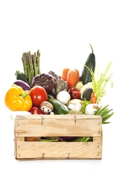 Assortment of fresh vegetables in a crate on white background
