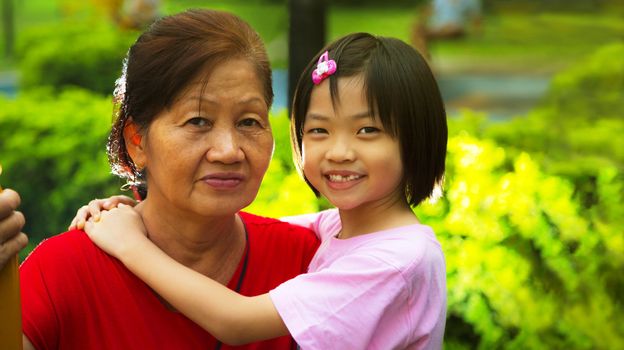 Grand daughter hugging Grandmother in the park.