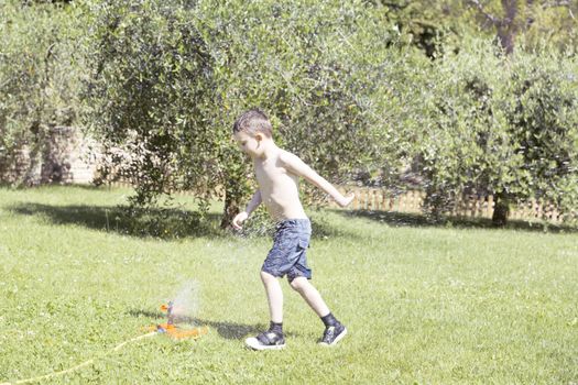 Happy Child Playing with Water in the Garden.