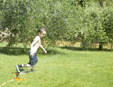 Happy Child Playing with Water in the Garden.