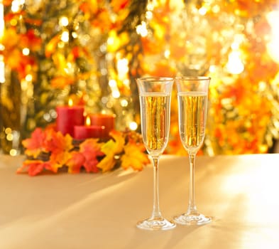 Champagne glasses for reception in front of autumn background and candles