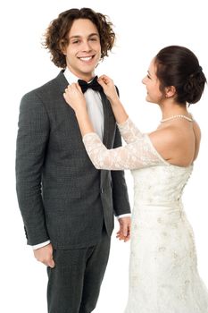 Attractive young bride adjusting the bow tie of her man
