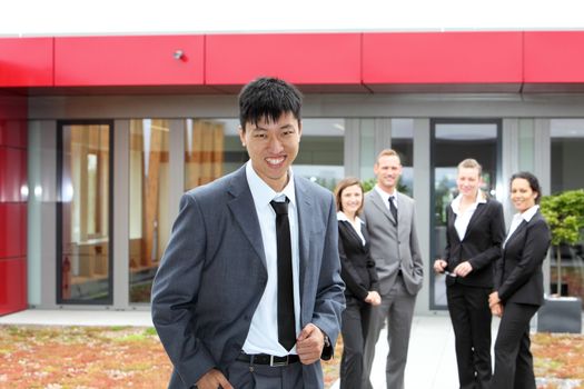 Smiling Chinese businessman with his colleagues at his back