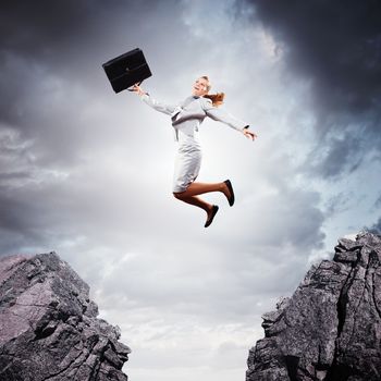 Image of young businesswoman jumping over gap