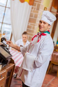 Image of handsome chef inserting card in terminal