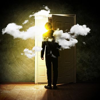 Image of young businessman standing with back opening door