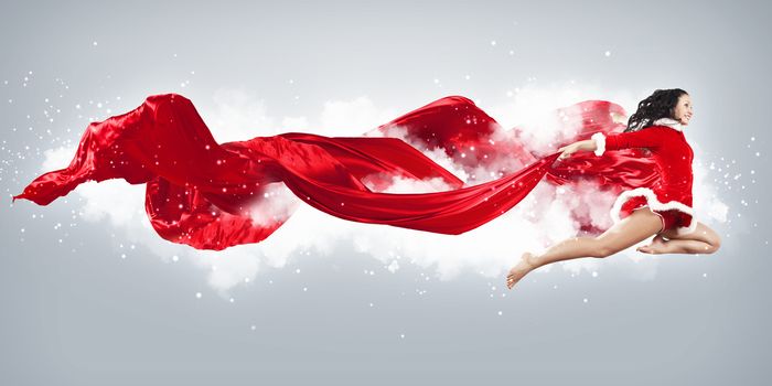 Happy smiling woman in red xmas costume jumping high