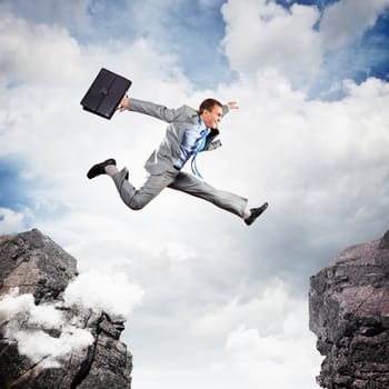 Image of young businessman jumping over gap