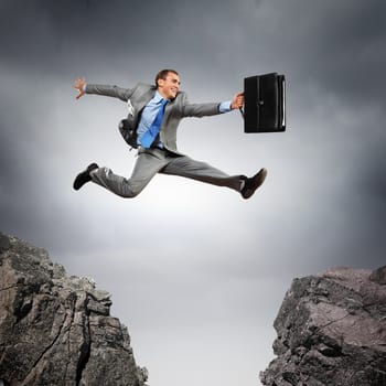 Image of young businessman jumping over gap