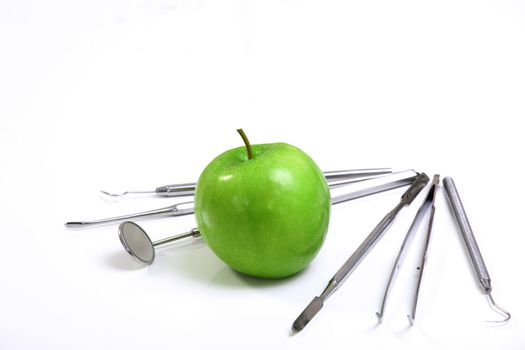 Green apple and dental tools isolated on white