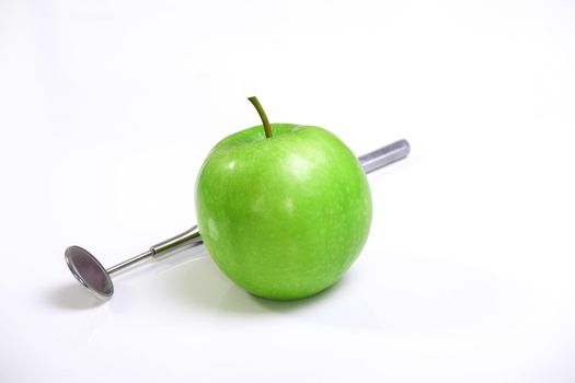Green apple and dental tools isolated on white