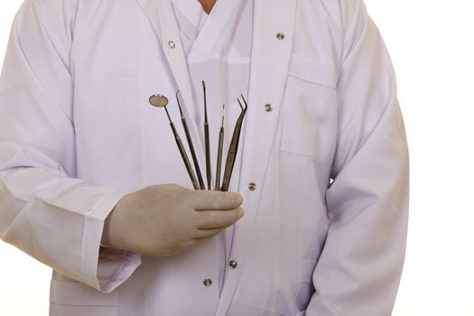 A dentists hands in white medical gloves with dental tools