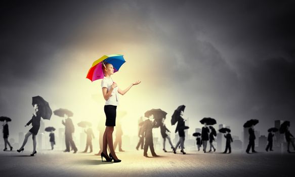 Image of pretty businesswoman with umbrella walking in crowd of people