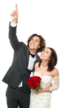 Smiling young groom pointing out something to his beloved wife