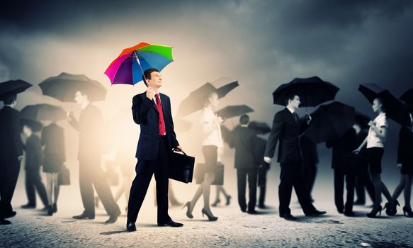 Image of pretty businessman with umbrella walking in crowd of people
