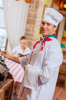 Image of handsome chef inserting card in terminal