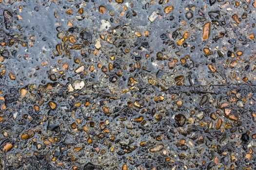 Wet sand and pebbles at sea shore. Textured background