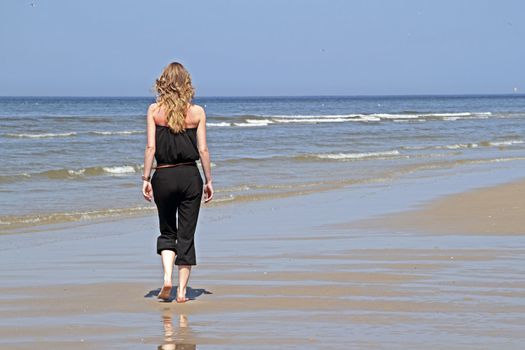 Young beautiful woman walking at the beach in the Netherlands