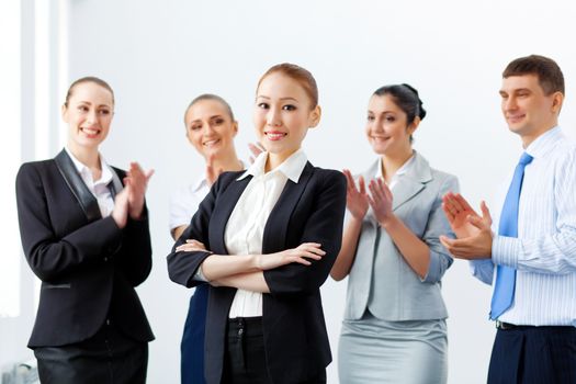 Young asian businesswoman smiling with colleagues applauding joyfully at background