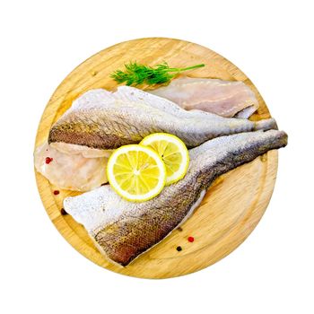 Fillet of cod on a round board with lemon and dill isolated on white background