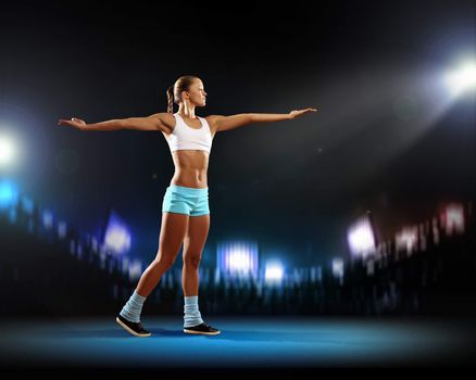 Fitness woman standing against stadium lights background