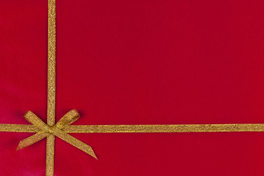 Red background of present wrapped with gold ribbon and bow