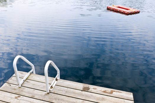 Dock and ladder on calm summer lake with diving platform in Ontario Canada