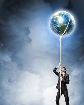 Image of businessman climbing rope attached to earth planet