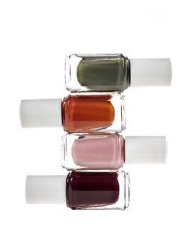 Nail polish bottles of various colors stacked isolated on white background