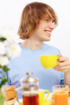 Young happy man drinking tea at home