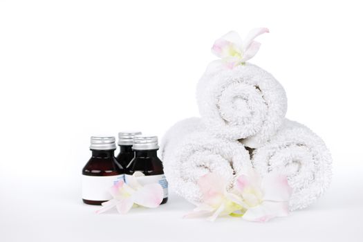 White rolled up spa towels and body care products with orchid flowers