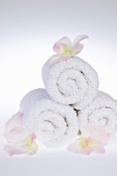 White rolled up spa towels with orchids flowers