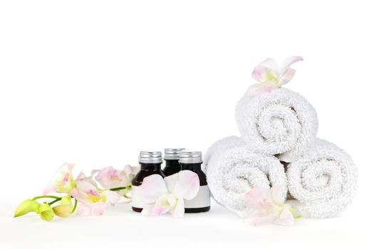 White rolled up spa towels and body care products with orchid flowers