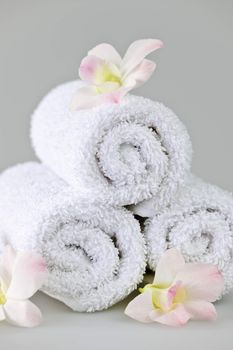 White rolled up spa towels with orchids flowers