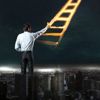Image of young businessman standing with back drawing ladder