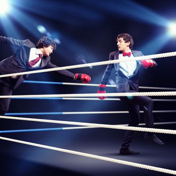 Two young businessman boxing againts dark background . conceptual collage