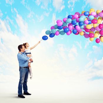 Image of happy father holding on hands daughter and balloons