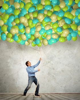 Image of adult man pulling rope with bunch of colorful balloons