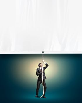 Image of young businessman pulling blank banner. Place for text