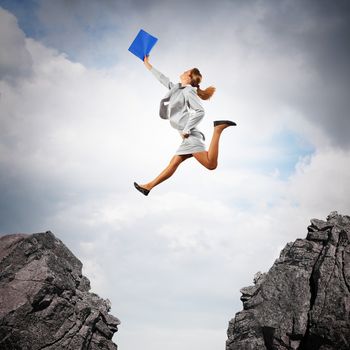 Image of young businesswoman jumping over gap