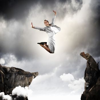 Image of young businesswoman jumping over gap