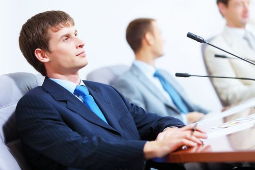 Image of three businesspeople at table at conference