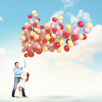 Image of father and daughter holding bunch of colorful balloons