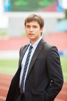 Satisfied smiling businessman standing in the summer outdoors.