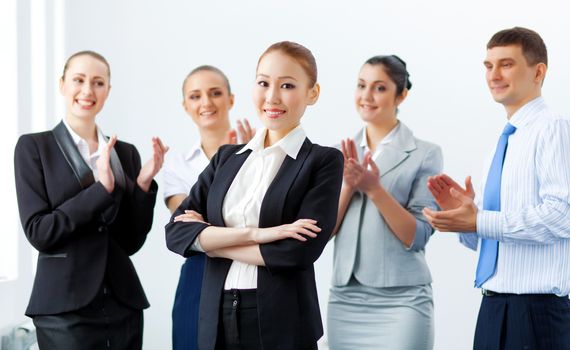 Young asian businesswoman smiling with colleagues applauding joyfully at background